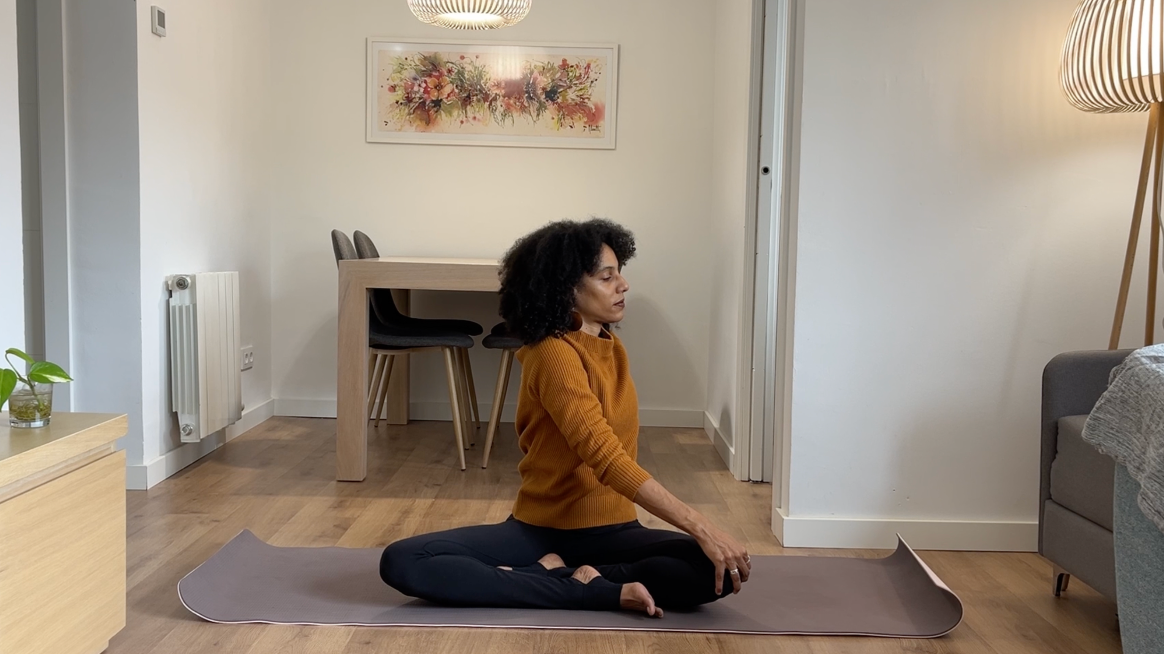 Laia Bové in an upright seated spinal twist with one hand placed on the opposite knee and the other resting behind her.